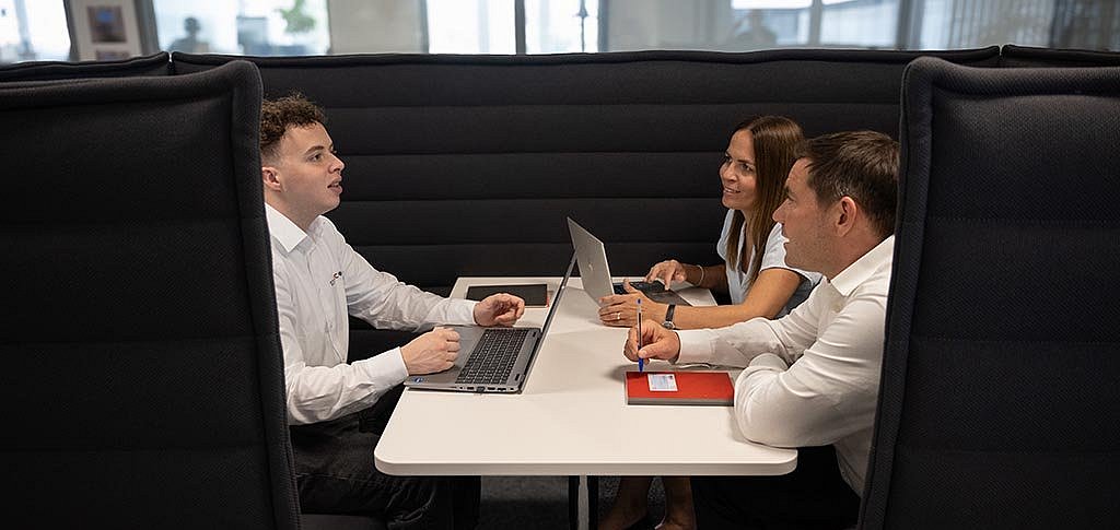 Colleagues sitting in a working booth talking about work