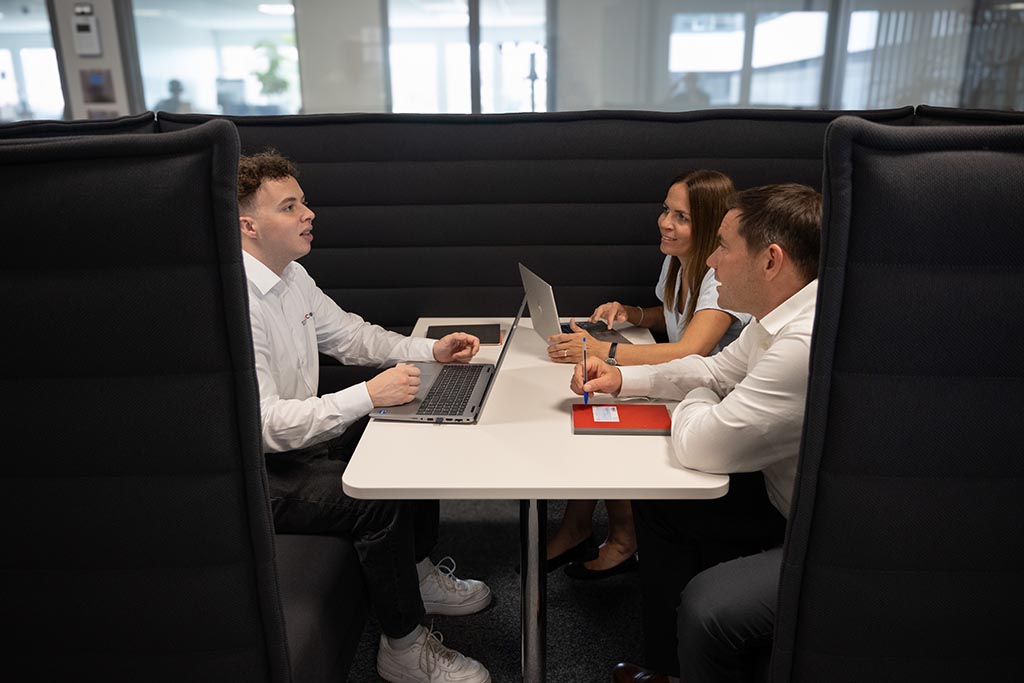 Colleagues sitting in a working booth talking about work
