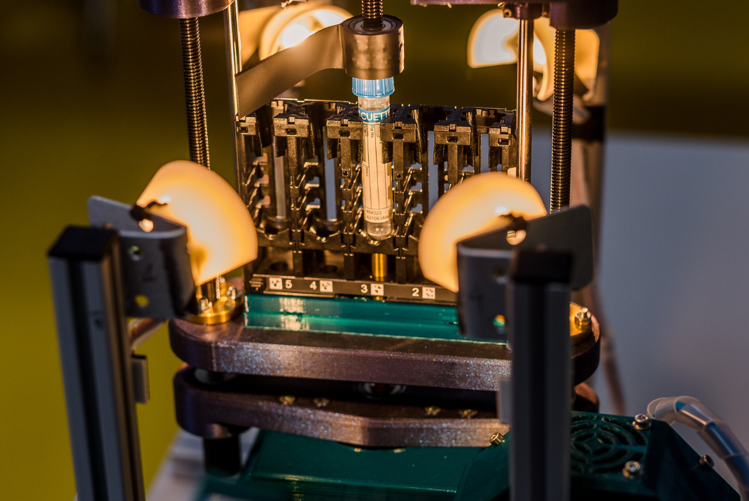 Close-up of a testing tube in a machine with lights towards the testing tube