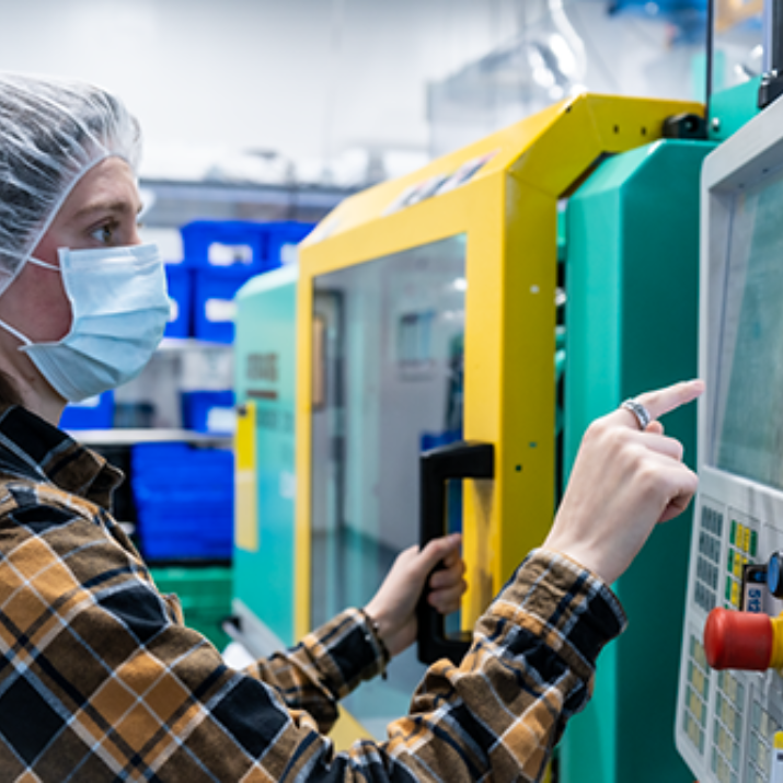 Natech colleague wearing a protective hood and mask operates a machine in the production hall