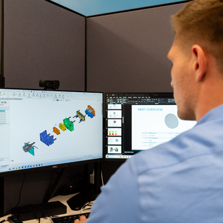 Natech employee looking at screens in front of him that is showing the individual assembly parts of a system