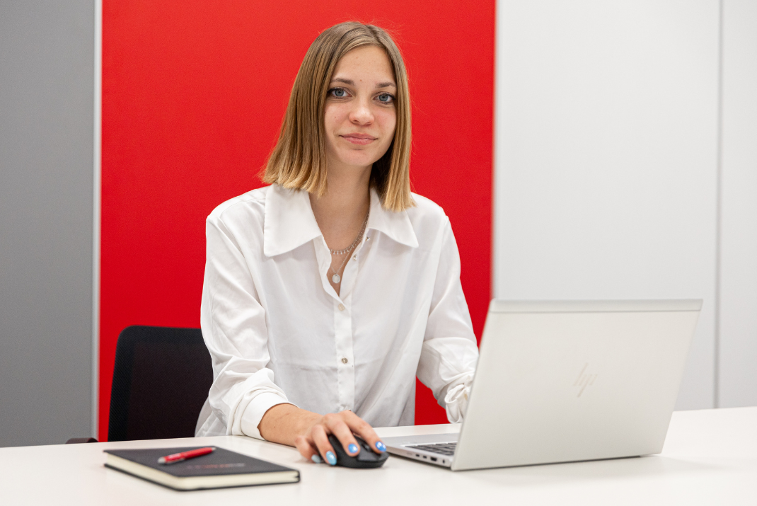 Evelin from Diatron smiling while sitting in front of her laptop 