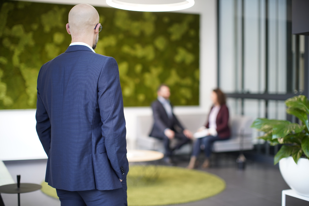 STRATEC employee looking at two other colleagues sitting on the sofa in the reception area
