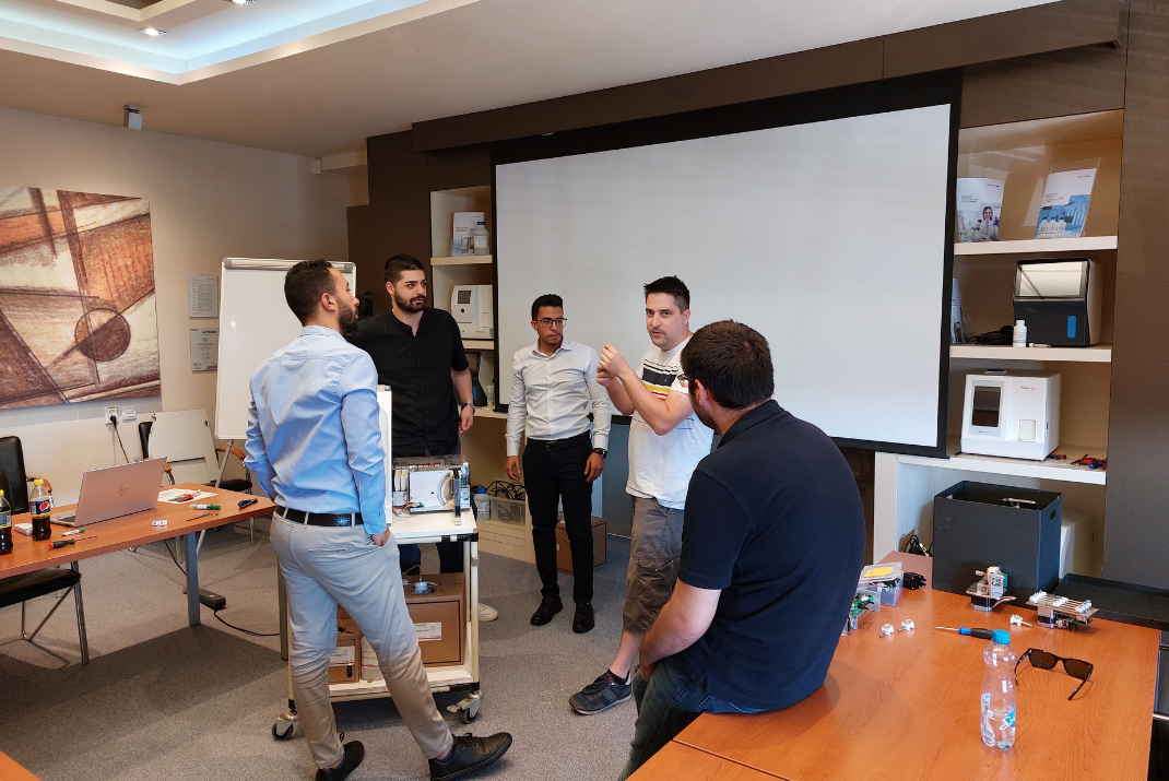Diatron employees in the office holding a meeting in front of a white canvas screen 