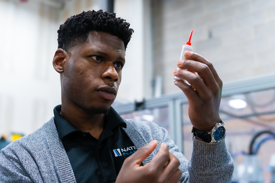 Natech employee holding a chemical in a tube with a red, pointed lid in his hand