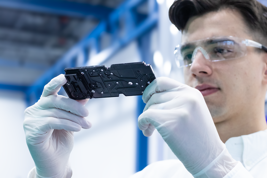 Natech employee with safety gloves and glasses inspecting an assembly piece
