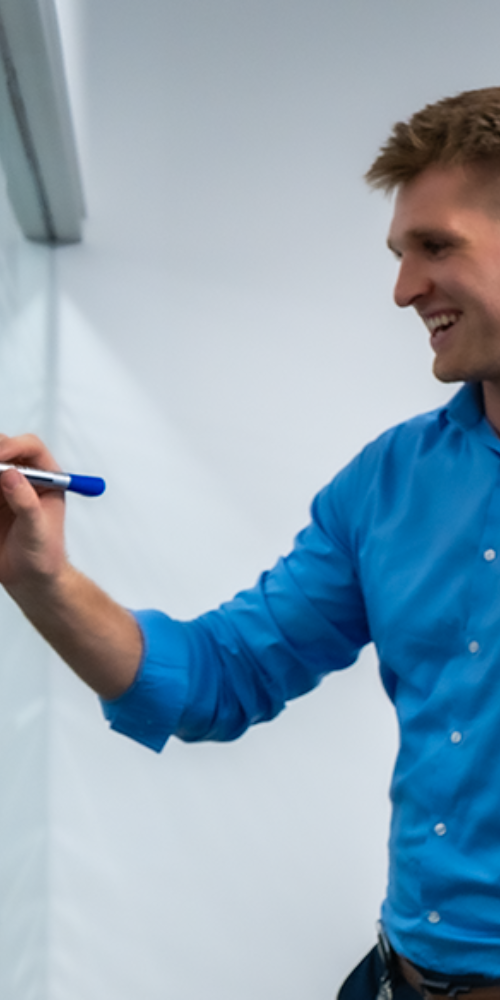 Employee with a blue pen in his hand, writing something on the flip chart