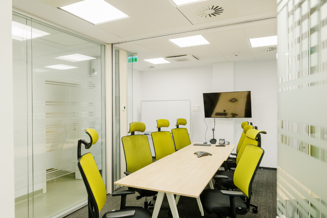 Big office with 6 green chairs and a TV screen in STRATEC Romania