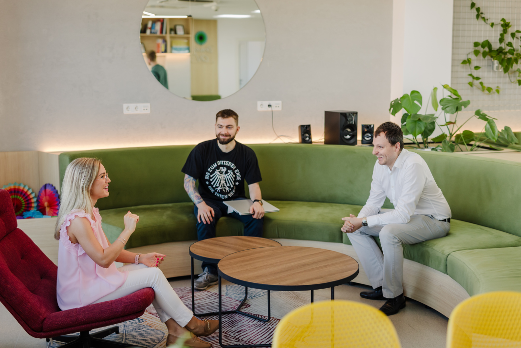 STRATEC employees having a small talk in the corporate lounge sitting on a green sofa